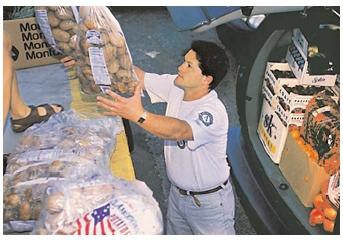 Workers prepare to redistribute surplus foods purchased by the U.S. Department of Agriculture. The USDA's commodity foods programs serve a dual purpose, maintaining the price of certain food products and ensuring that at-risk populations get the food they need. [Photograph by Ken Hammond. USDA. Reproduced by permission.]